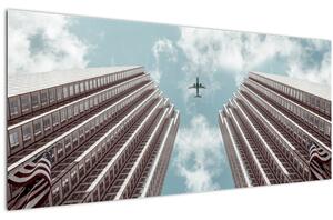 Repülőgép az épületek között képe (120x50 cm)