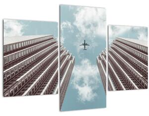 Repülőgép az épületek között képe (90x60 cm)