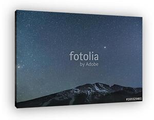 Star filled sky over snowy mountains at night (vászonkép)