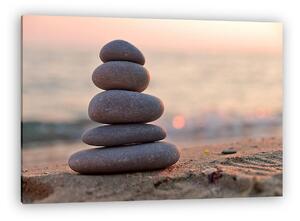 Stacked stones on the beach at sunset (vászonkép)