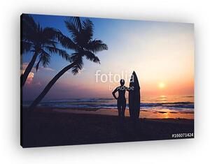 Silhouette women surfer on tropical beach at sunset. landscape of summer beach and palm tree at sunset. vintage color tone (vászonkép)