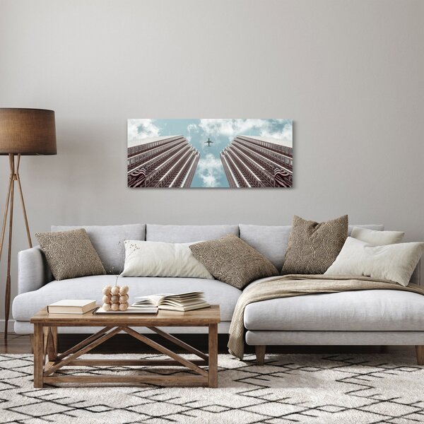 Repülőgép az épületek között képe (120x50 cm)