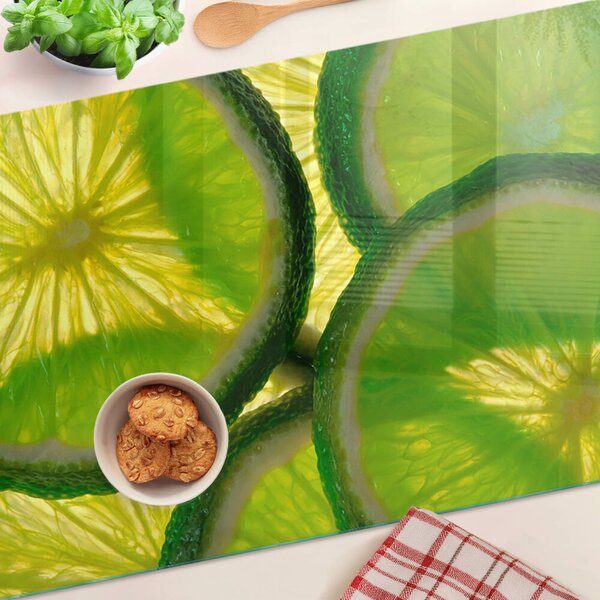 Üveg vágódeszka fényképpel Lime szeletek zöld háttéren